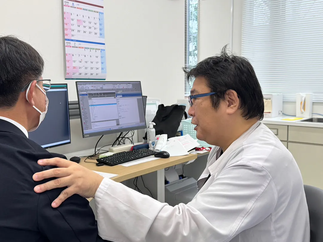肩に手を添えて話す院長